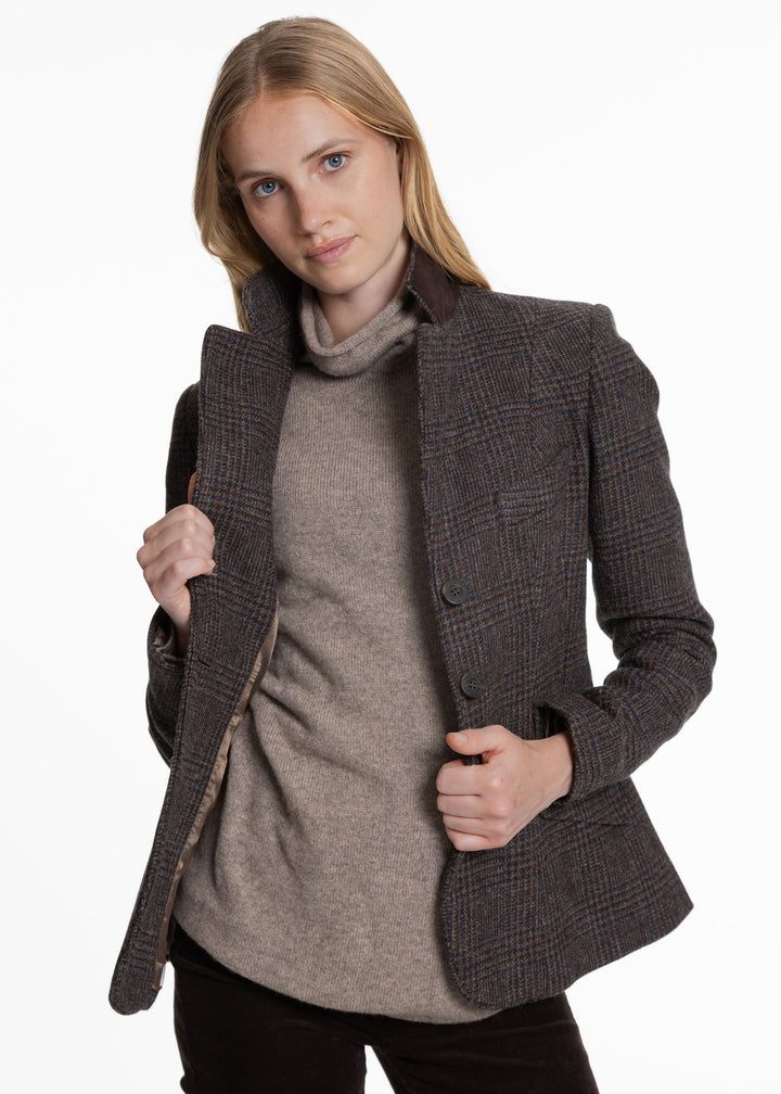 A woman modeling a dark brown and gray plaid jacket over a taupe turtleneck sweater, shown against a plain white studio background.