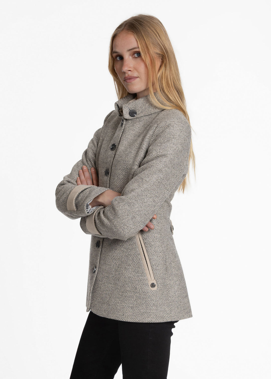 A woman modeling a light gray twill jacket with a high collar and dark buttons, paired with black pants, against a plain white background.
