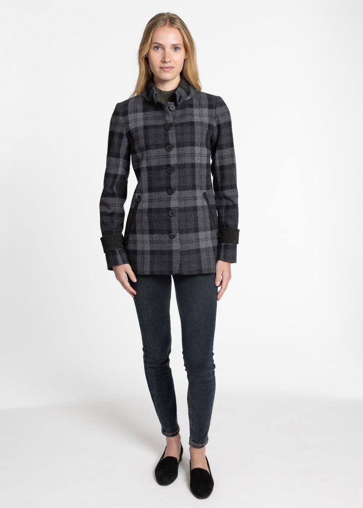 A woman modeling a dark gray and black plaid button-front jacket with a high collar, paired with dark skinny jeans and black flats, against a plain white studio background.