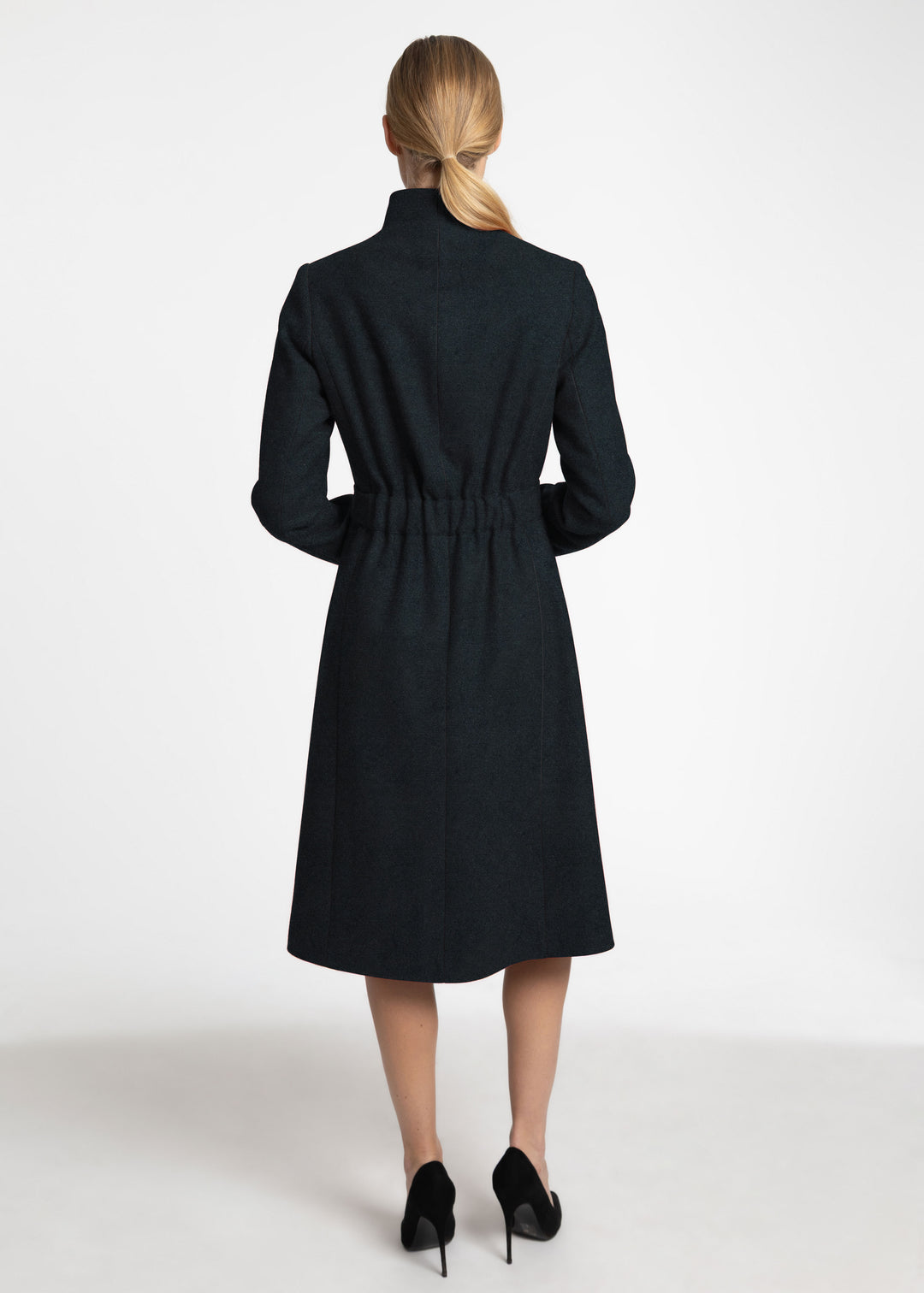 Back view of a woman wearing a dark green wool coat.
