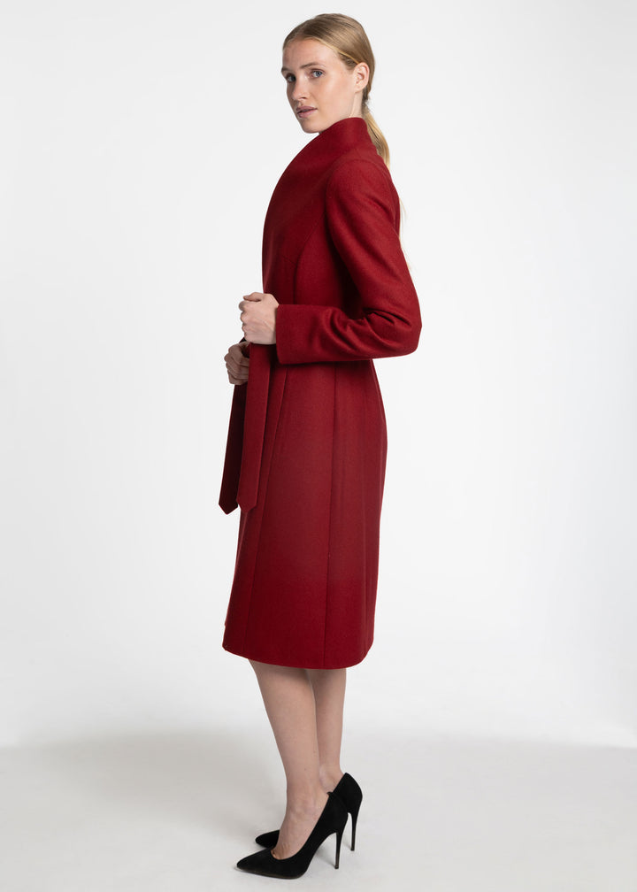 A woman modeling a long-sleeved, knee-length red coat with a shawl collar, shown from a side-back angle against a plain white studio background.