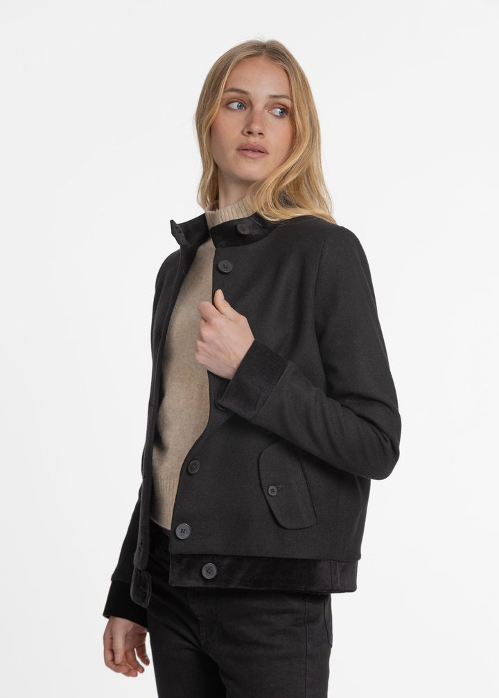 Model wearing black jacket with high collar and buttons