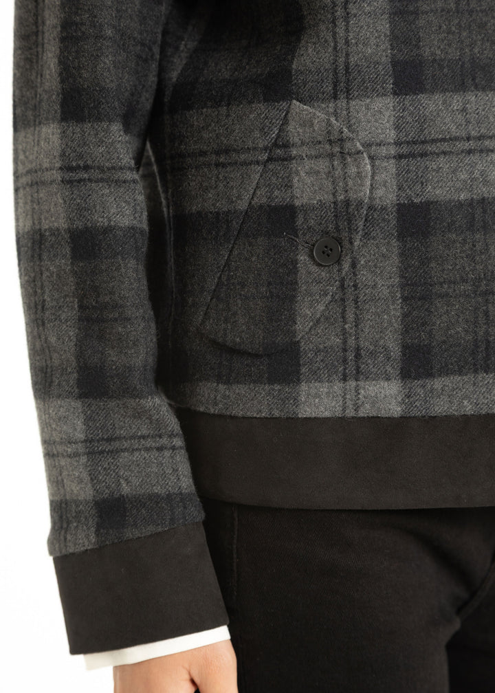 Close up of grey and black check fabric and side pocket with black button.