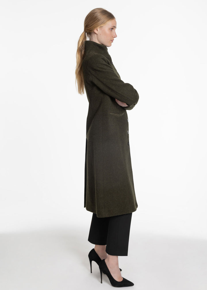 Side view of a woman wearing a dark green wool coat on a white background.