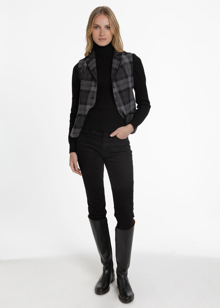 Woman modeling a black and grey plaid waistcoat over a black turtleneck.