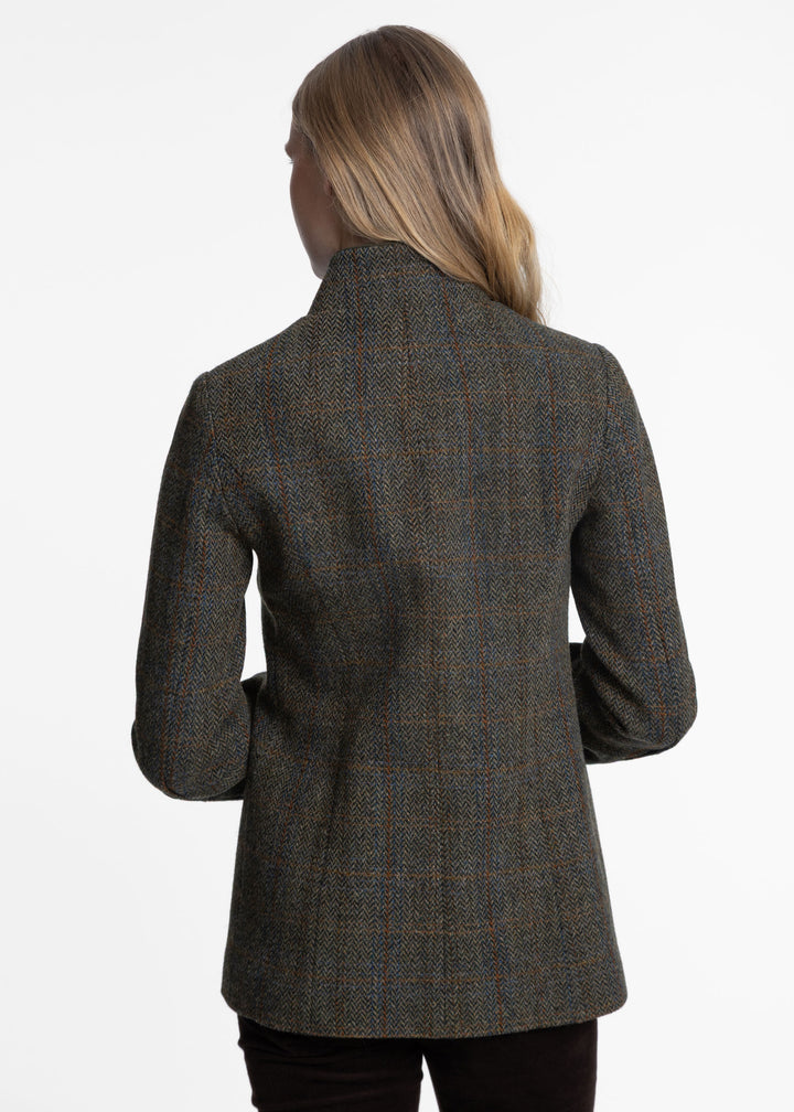 A woman viewed from the back wearing a dark green tweed jacket with a subtle red and blue windowpane pattern, set against a plain white studio background.