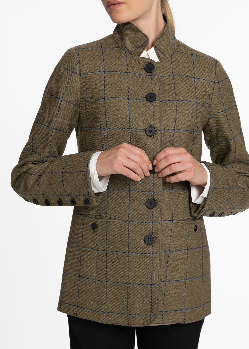 A woman wearing a green and blue tweed windowpane jacket with a high stand collar and black buttons, styled over a white collared shirt.