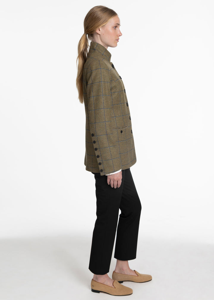 A side view of a woman wearing a green and blue check wool jacket with black buttons in the front and on the sleeves.