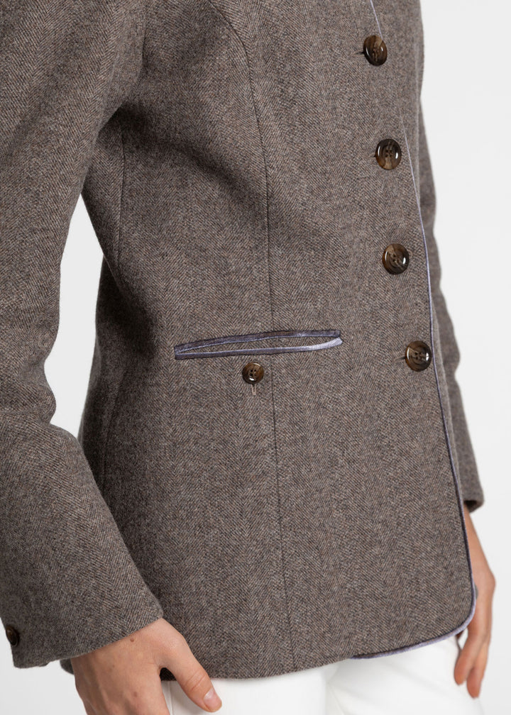 Close-up of a purple-grey tweed jacket with dark brown buttons and a purple velvet trim, worn by a model.