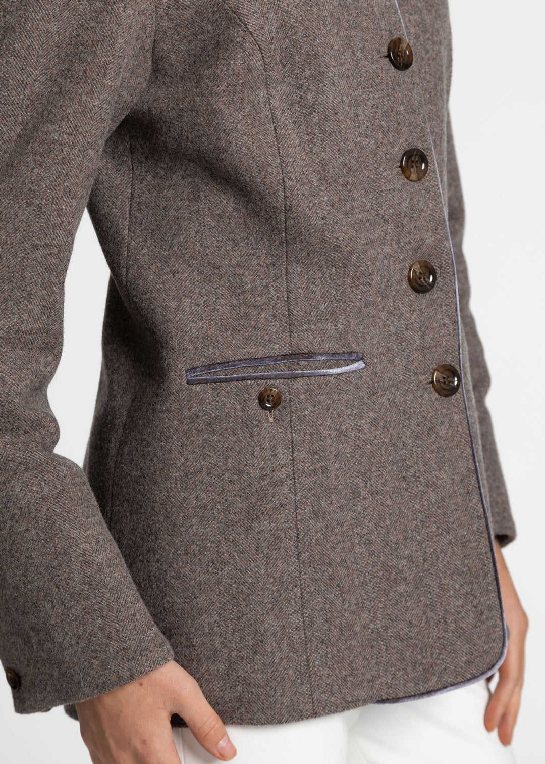 Close-up of a purple-grey tweed jacket with dark brown buttons and a purple velvet trim, worn by a model.