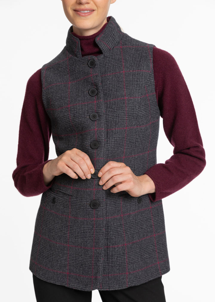 A woman wearing a dark gray and burgundy checkered waistcoat over a burgundy turtleneck sweater, shown from the chin down against a plain white background.