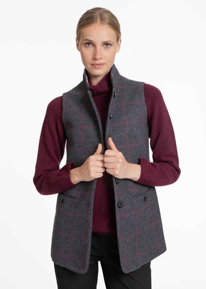 A woman modeling a dark gray windowpane plaid waistcoat over a burgundy turtleneck sweater and black pants, set against a plain white studio background.