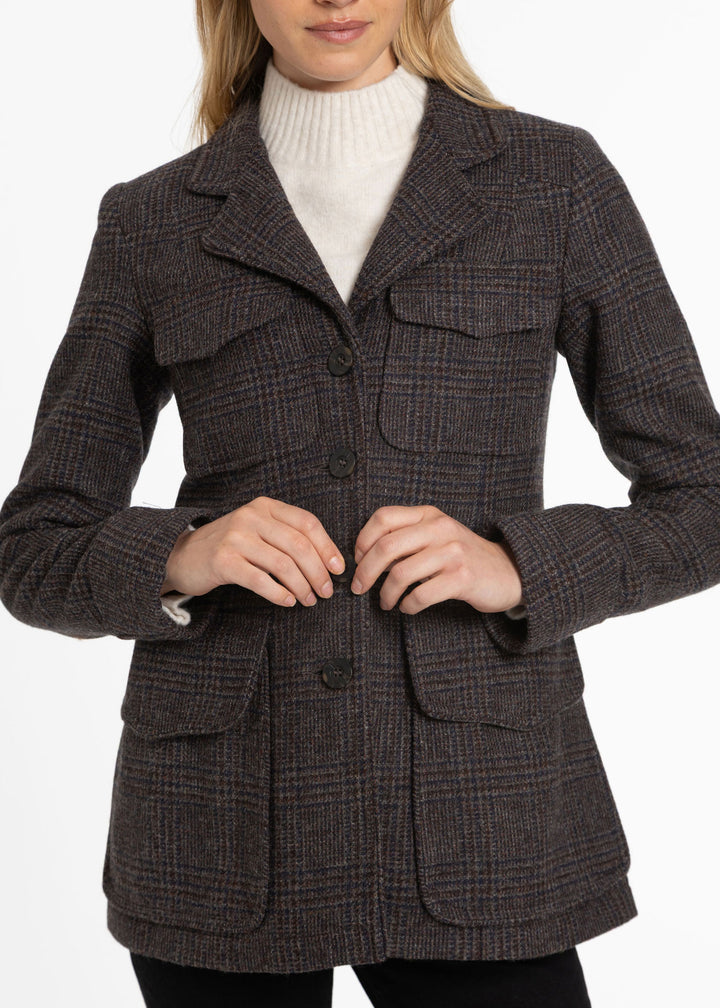 Close up of a brown and black checked jacket with four large front pockets and buttons down the front.