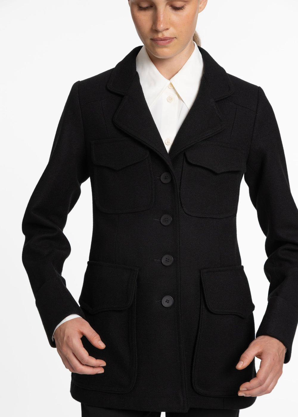 Close up of black jacket with four front pockets and black buttons down the front.