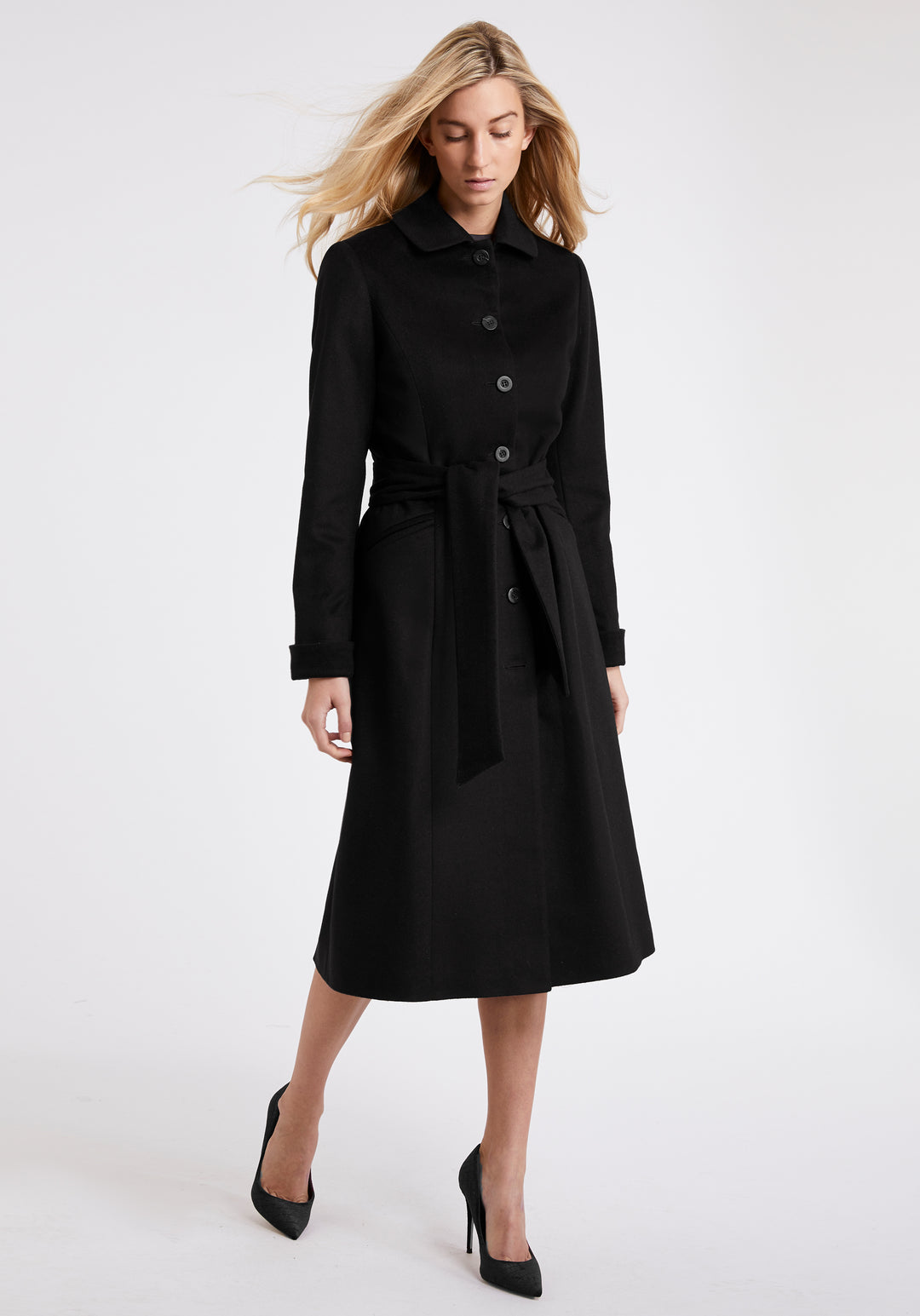 A model wears the Belted coat in black wool cashmere, featuring a slim fit with waist-cinching belt, deep turn-back cuffs and generous back vent.