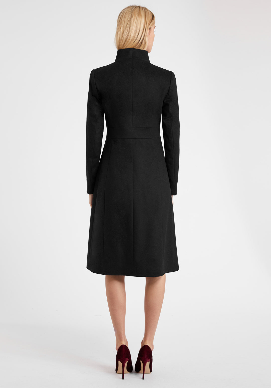 A model wears the Buxton coat in black wool cashmere, an elegant occasionwear style featuring a standing collar and deep suede cuffs.