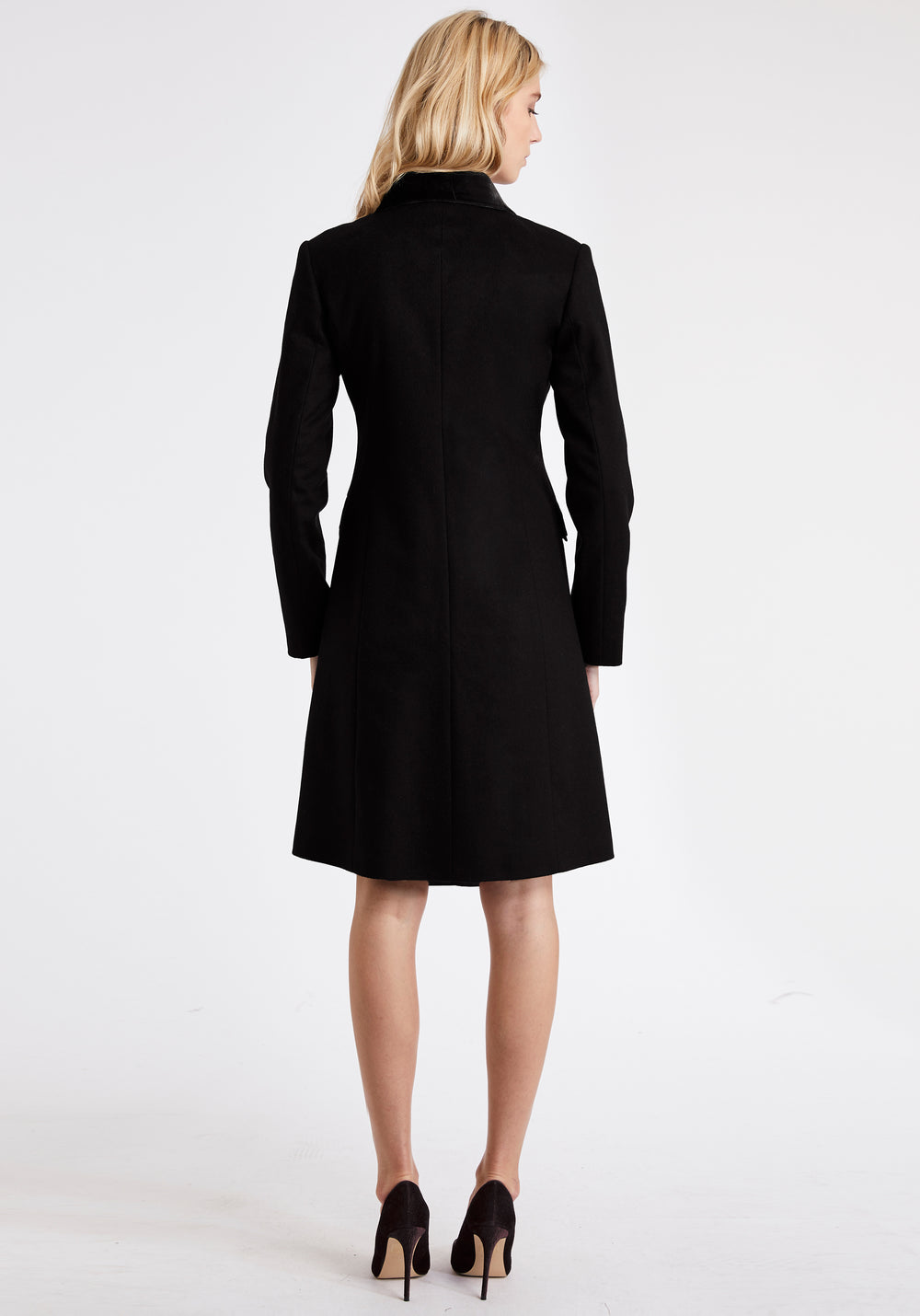 A model wears the Campbell coat, a neat, tailored design made from a black cashmere blend and finished with silk velvet detailing on the collar and pockets.