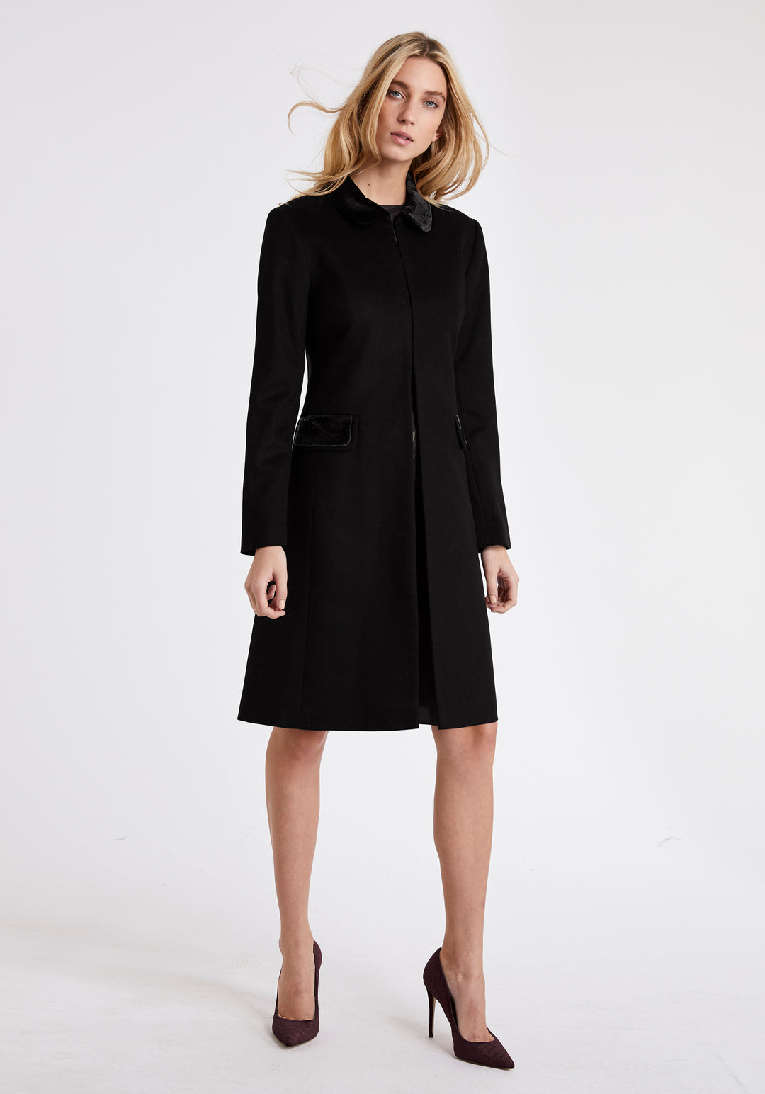 A model wears the Campbell coat, a neat, tailored design made from a black cashmere blend and finished with silk velvet detailing on the collar and pockets.