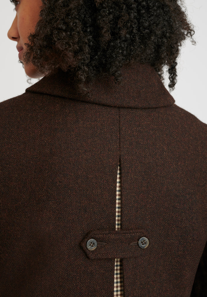 Brown coat close-up with a decorative button fastening detail on the back. Check fabric peaking through