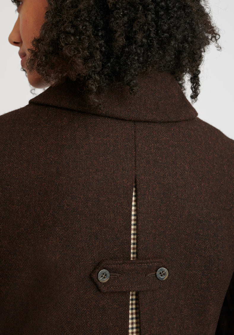 Brown coat close-up with a decorative button fastening detail on the back. Check fabric peaking through