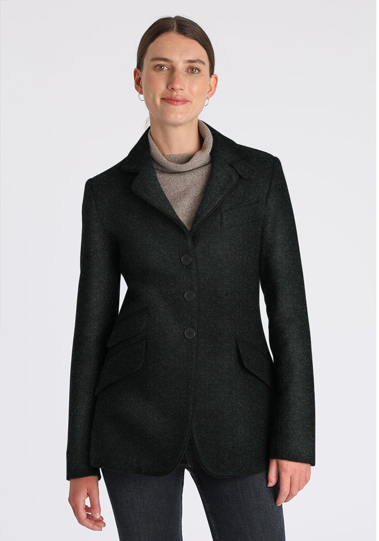 Woman wearing a green wool jacket with black buttons and piping