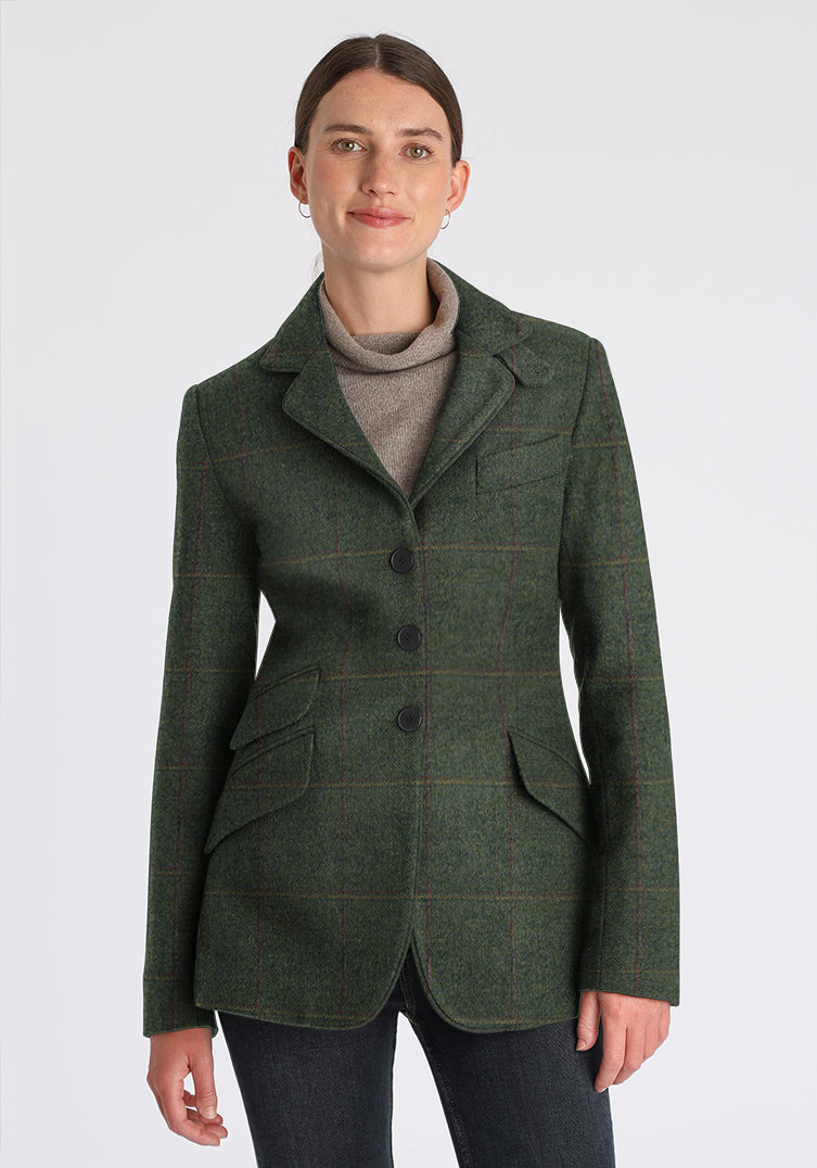 Woman wearing green wool jacket with faint yellow and red overcheck. Slate buttons down the front