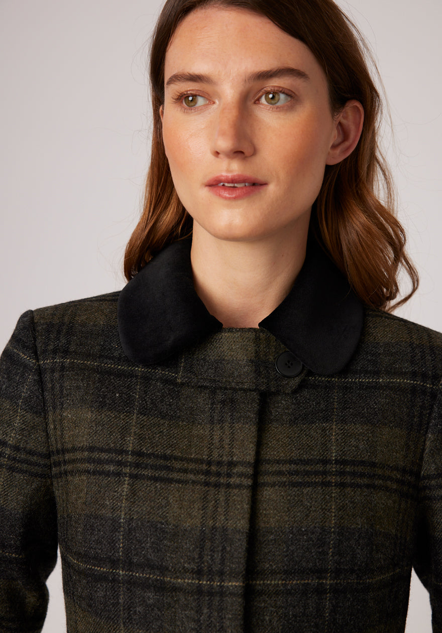 Close up of a grey and green check wool coat with a cotton velvet black detailing around the collar