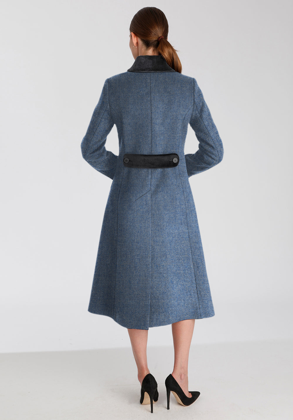 Back of woman wearing blue wool coat with dark grey collar and back belt detailing