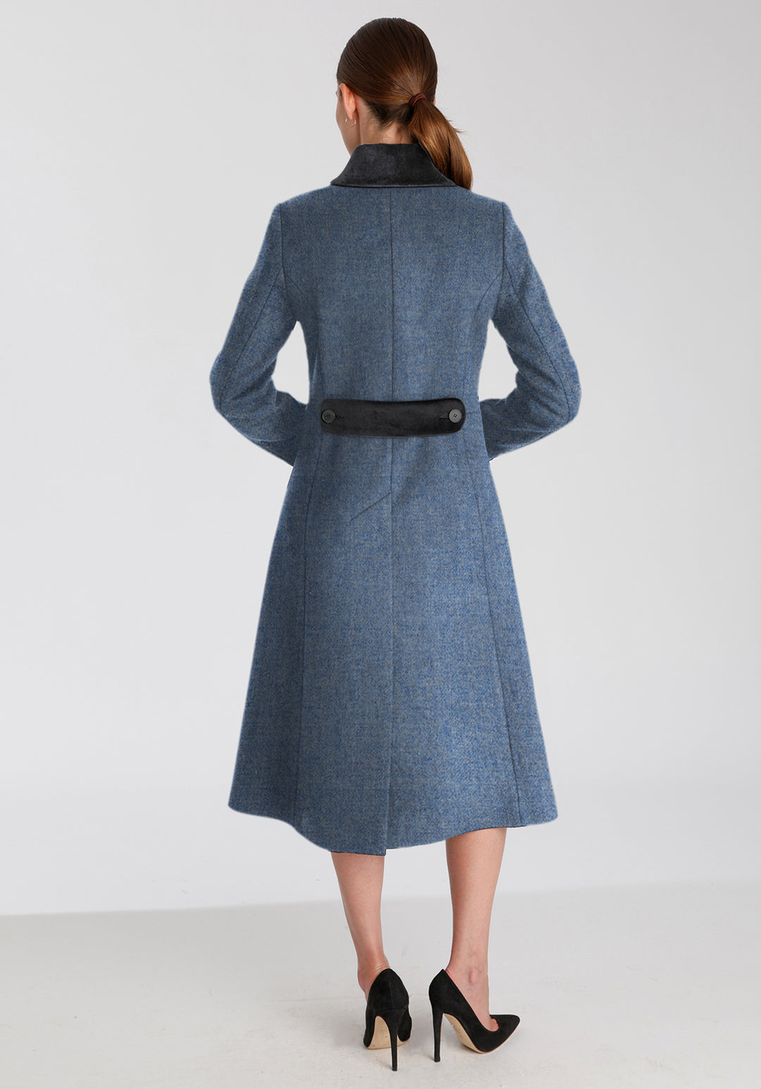 Back of woman wearing blue wool coat with dark grey collar and back belt detailing