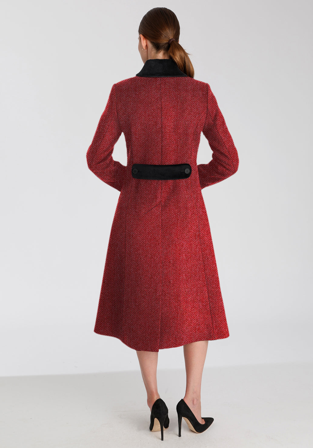 Back of woman wearing red and pink herringbone coat with black detailing on the collar and back belt
