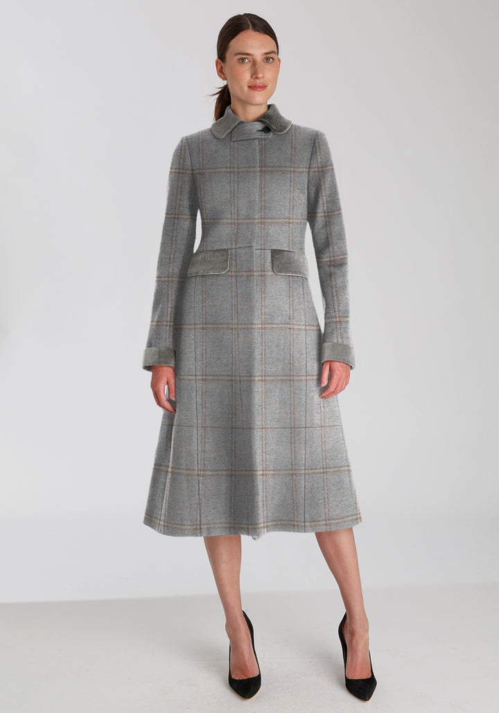 Woman wearing blue check coat with silver grey collar, pocket, and cuff detailing