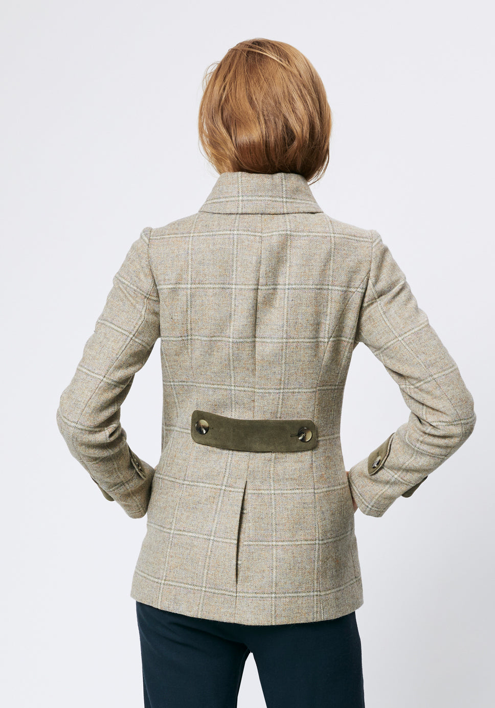 Woman wearing a cream check jacket with moss green back belt detail.