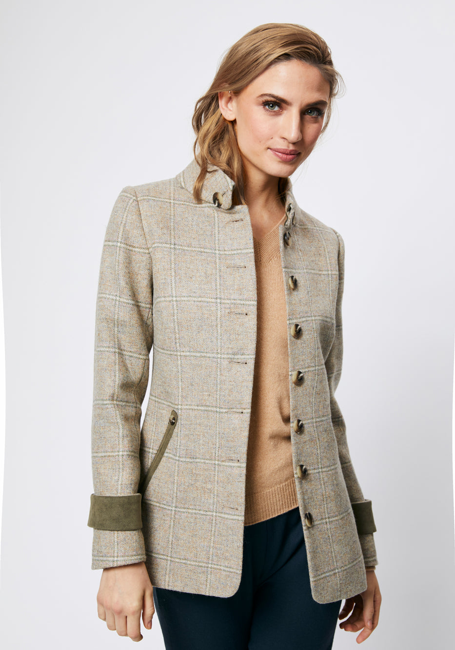 Woman wearing a cream check jacket with moss green cuff and pocket jets details and button down the front