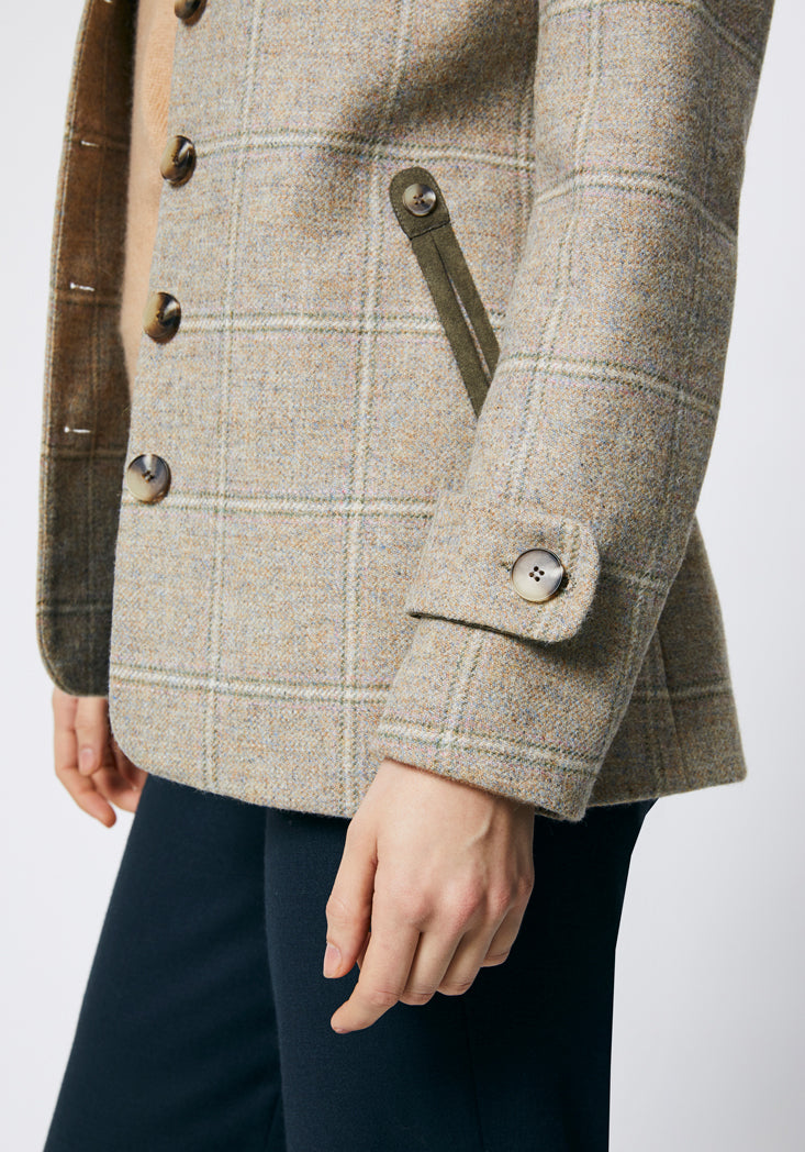 Close up on the side of a cream check jacket with cuff detailing ang moss green trim around the pockets