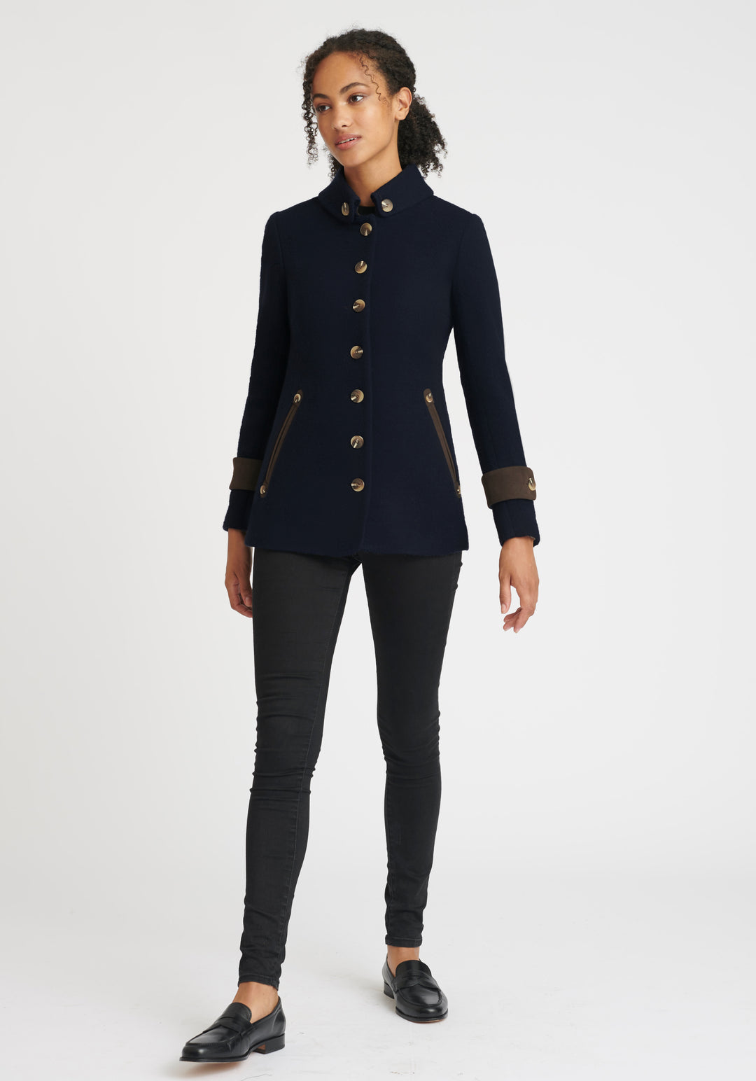 A model wears the Hendre jacket in navy, a structured, slim-fit design with high collar and suede trim.