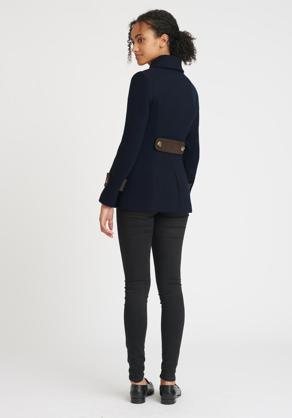 A model wears the Hendre jacket in navy, a structured, slim-fit design with high collar and suede trim.