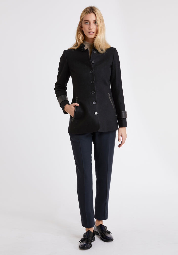 A model wears the Hendre jacket in black, a structured, slim-fit design with high collar and suede trim.