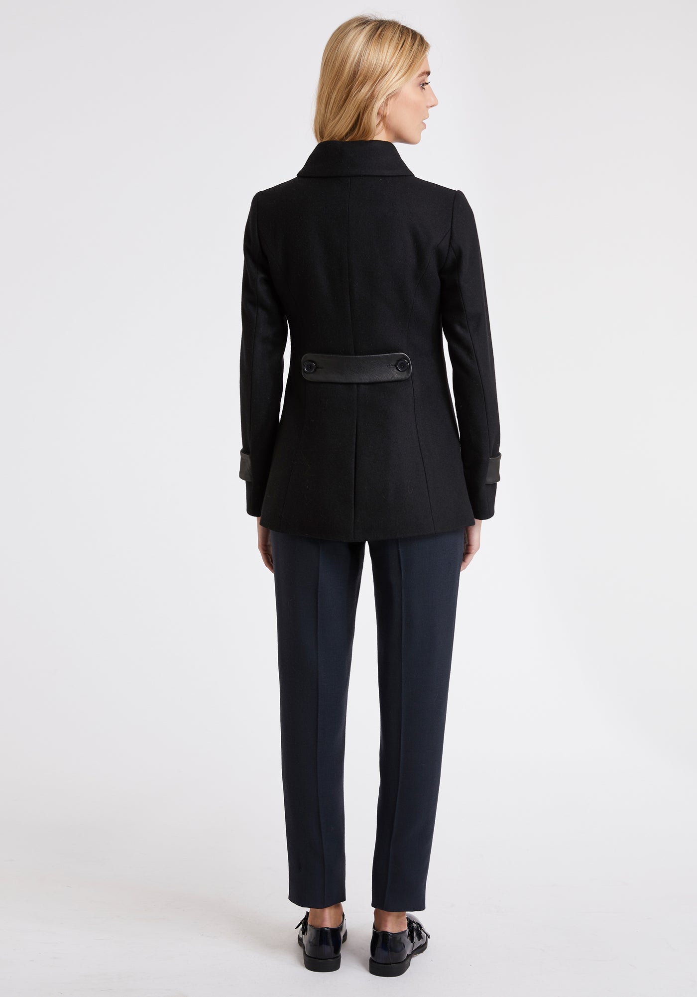 A model wears the Hendre jacket in black, a structured, slim-fit design with high collar and suede trim.