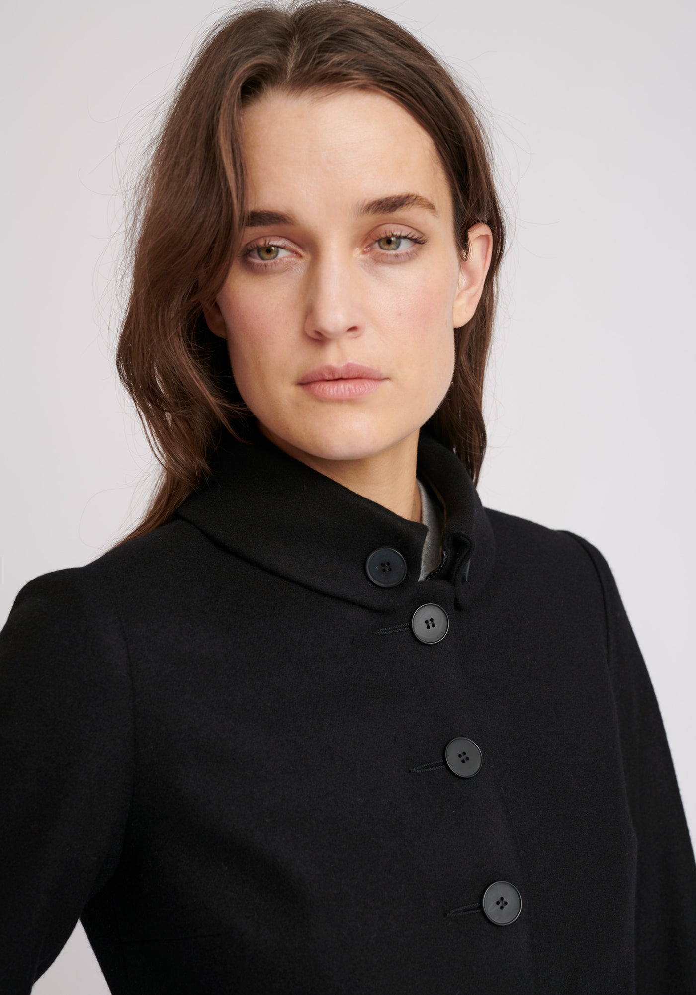 A model wears the Hendre jacket in black, a structured, slim-fit design with high collar and suede trim.