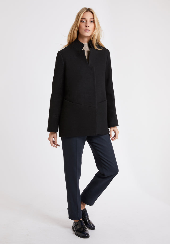 A model wears the Jackson jacket in black, a structured piece with unique cut-out standing collar and deep panelling on the body and cuffs.