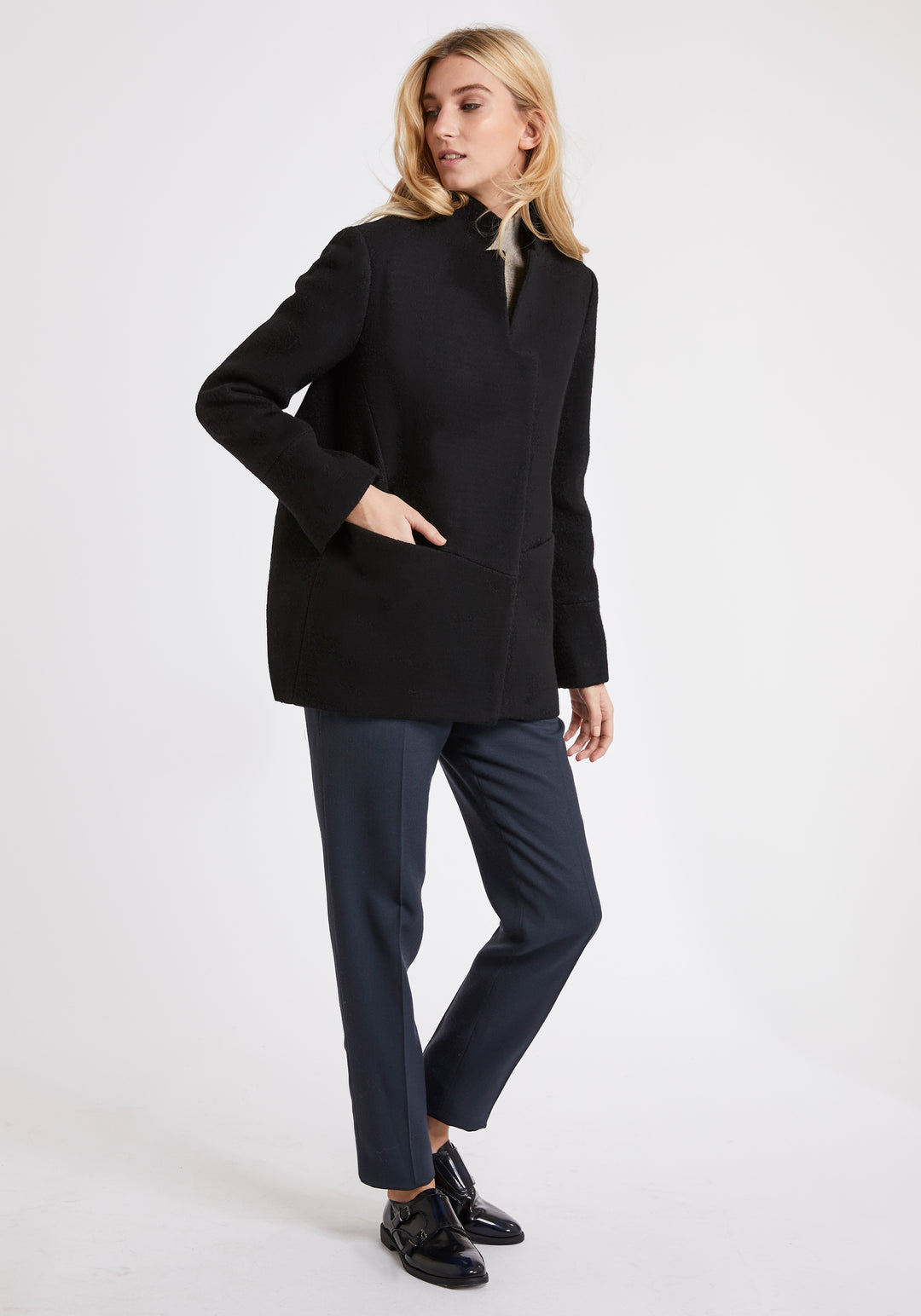 A model wears the Jackson jacket in black, a structured piece with unique cut-out standing collar and deep panelling on the body and cuffs.