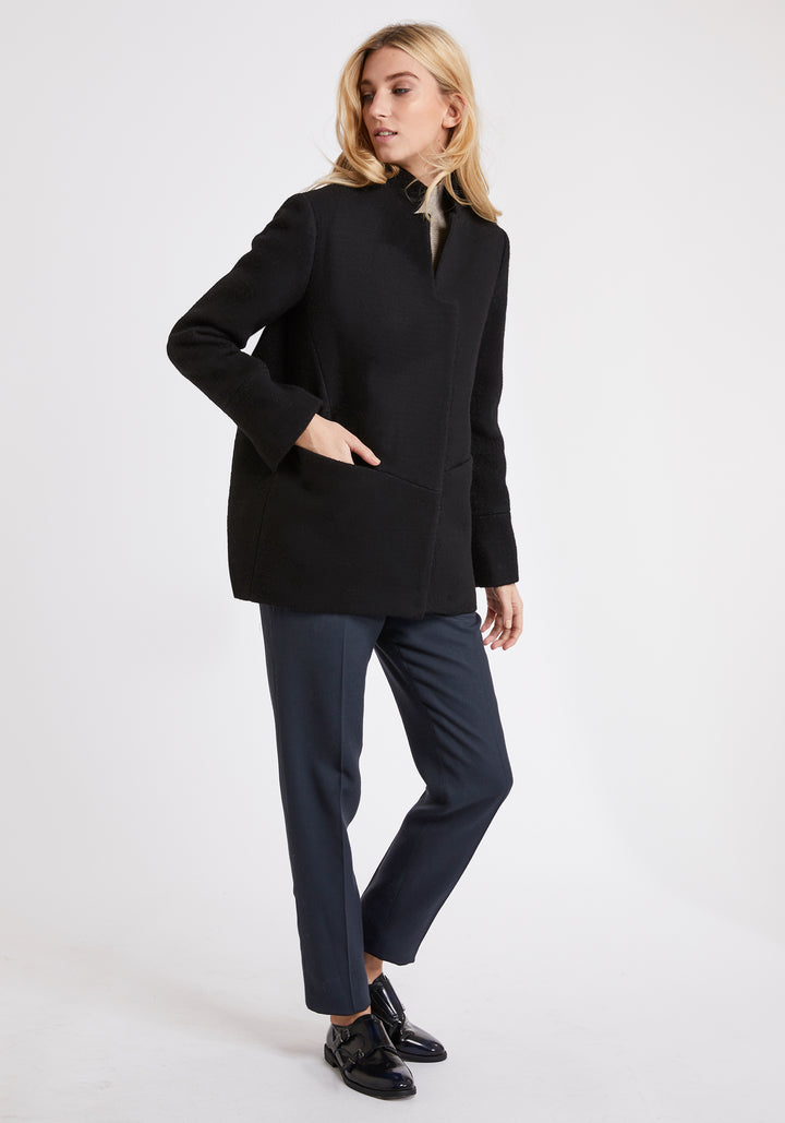 A model wears the Jackson jacket in black, a structured piece with unique cut-out standing collar and deep panelling on the body and cuffs.