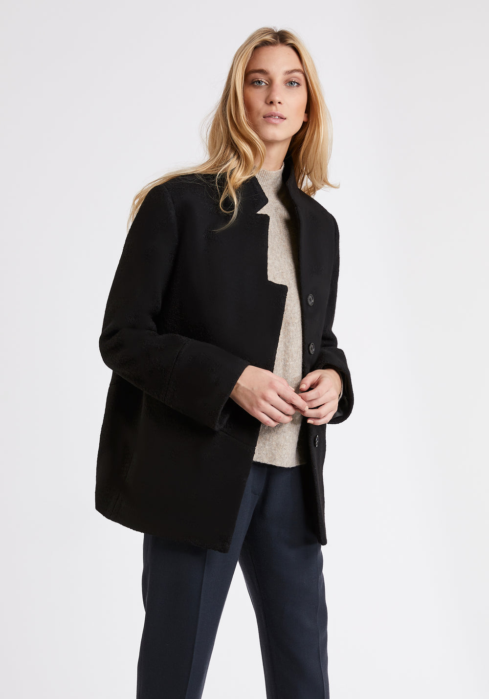 A model wears the Jackson jacket in black, a structured piece with unique cut-out standing collar and deep panelling on the body and cuffs.