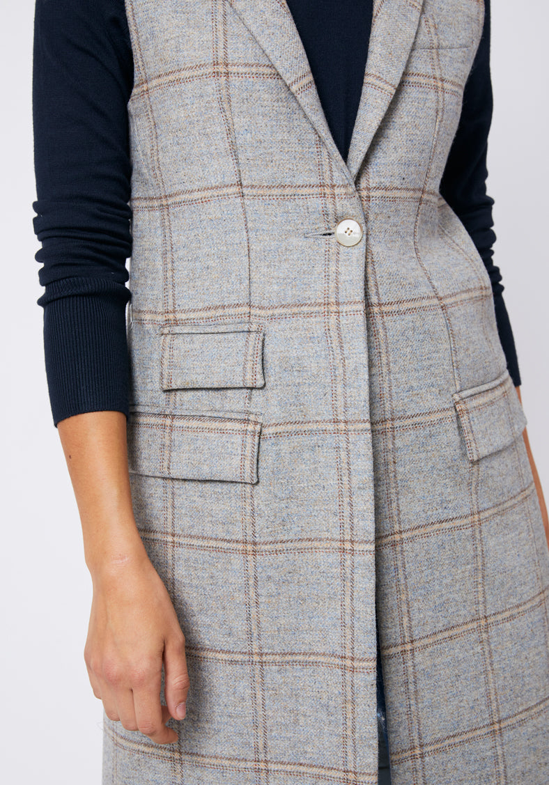 Close up of a blue grey checked waistcoat with a singular ivory button