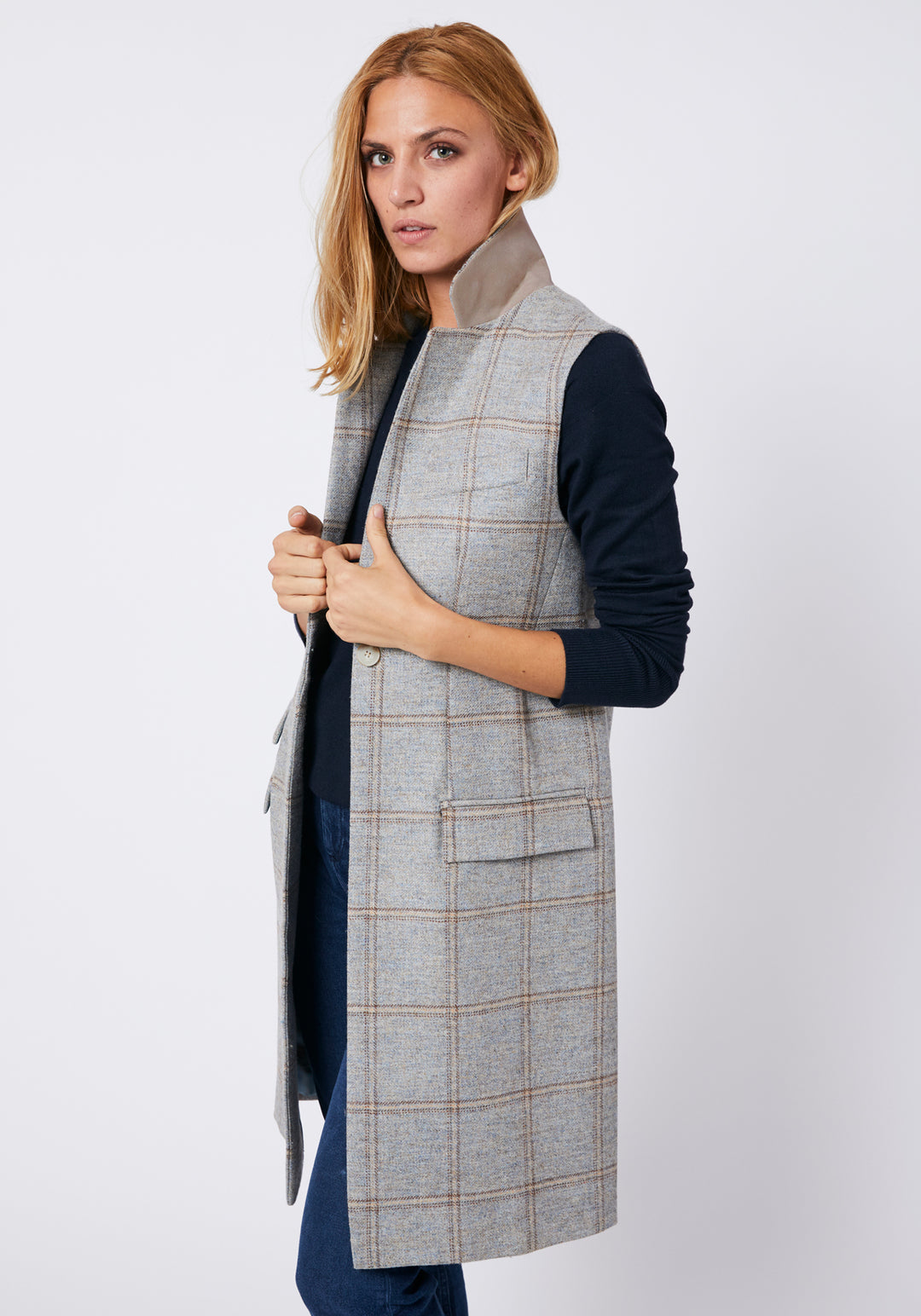 Woman wearing a blue grey check waistcoat with sandy cream under collar detail