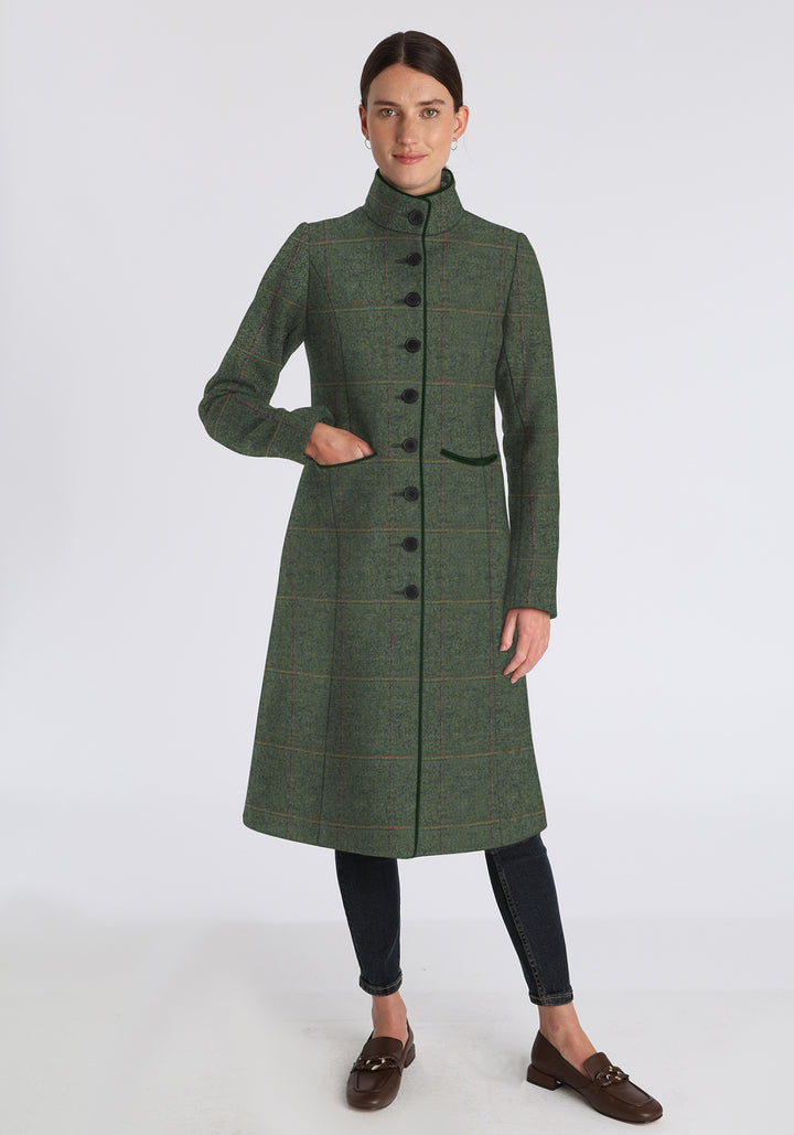 Woman wearing a green coat with yellow and red overcheck on a white background