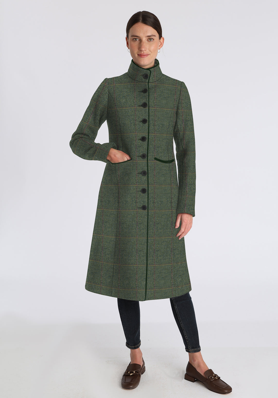 Woman wearing a green coat with yellow and red overcheck on a white background