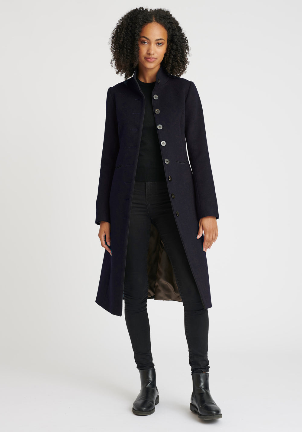 A model wears the Opera coat, a fitted, longline coat made from thick navy merino wool.