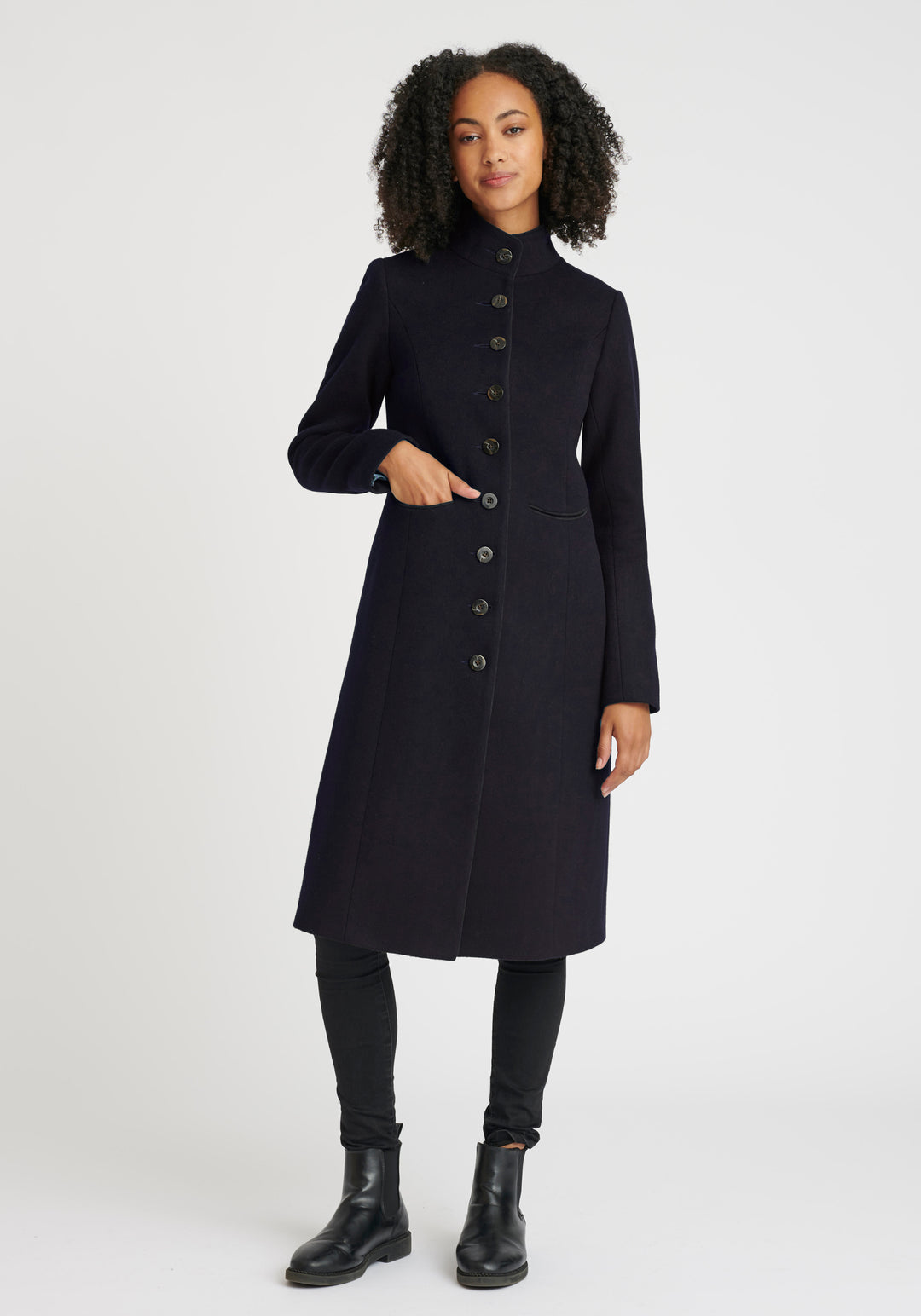 A model wears the Opera coat, a fitted, longline coat made from thick navy merino wool.