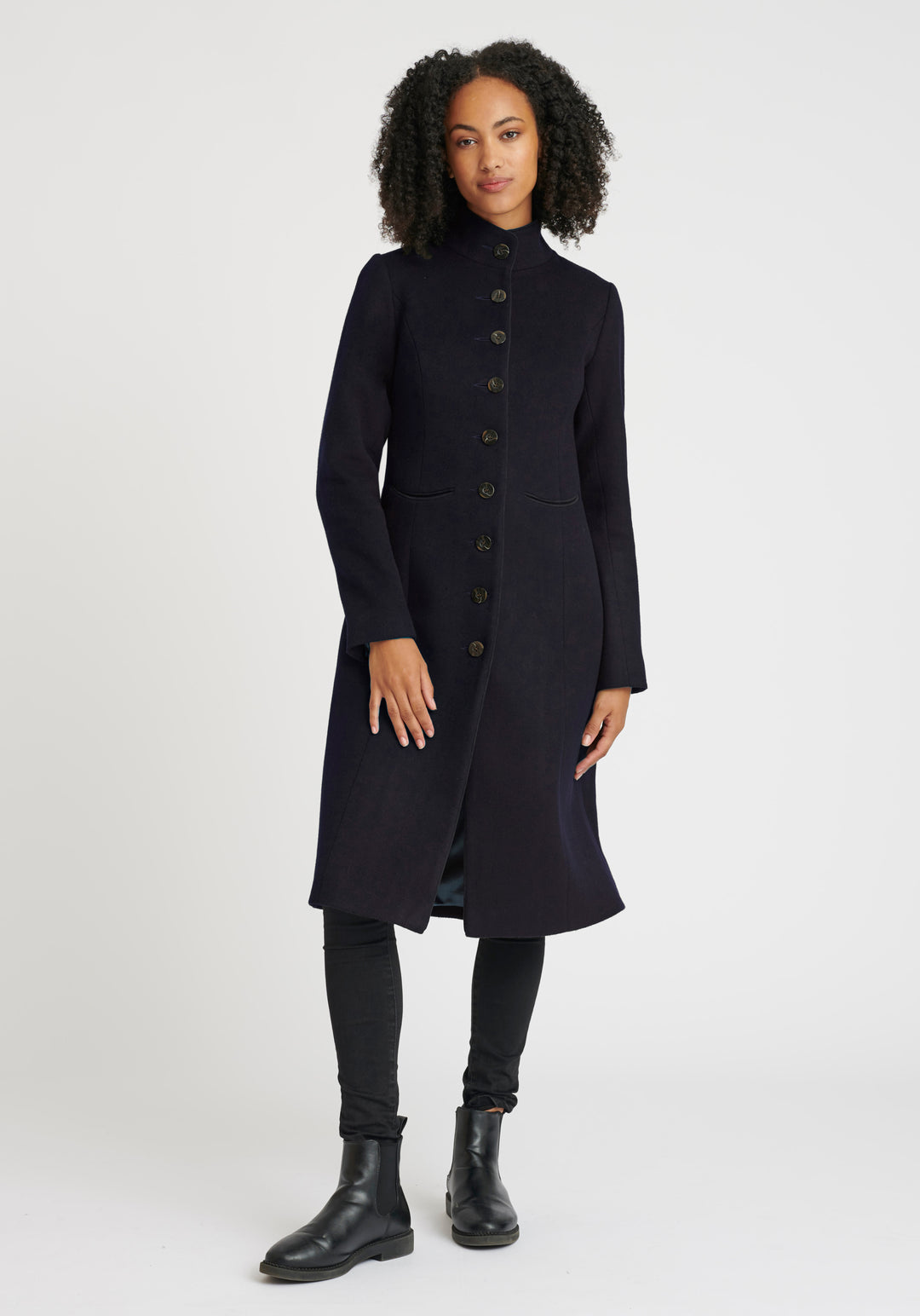 A model wears the Opera coat, a fitted, longline coat made from thick navy merino wool.